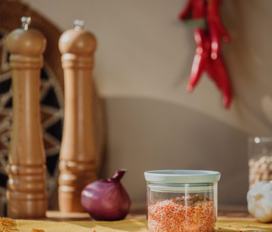 side view of a glass jar with red lentils on a wooden table